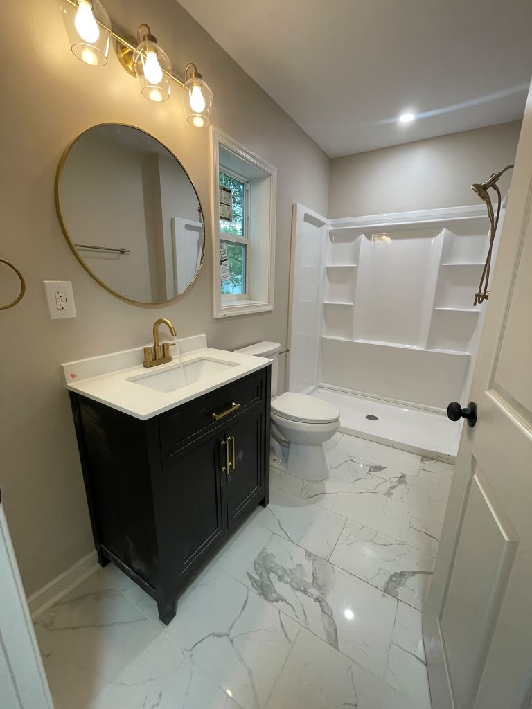 Bathroom remodel with black vanity and gold fixtures